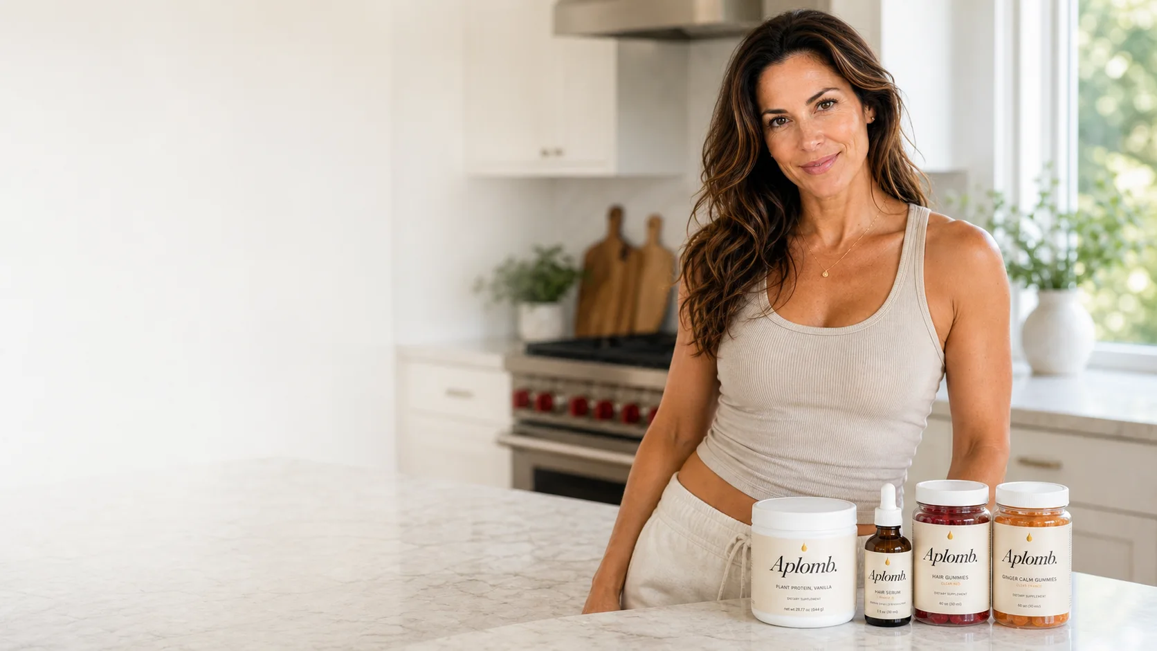A woman in her kitchen with the four-product Aplomb system: Protein, Facial Serum, Roots, and Calm.