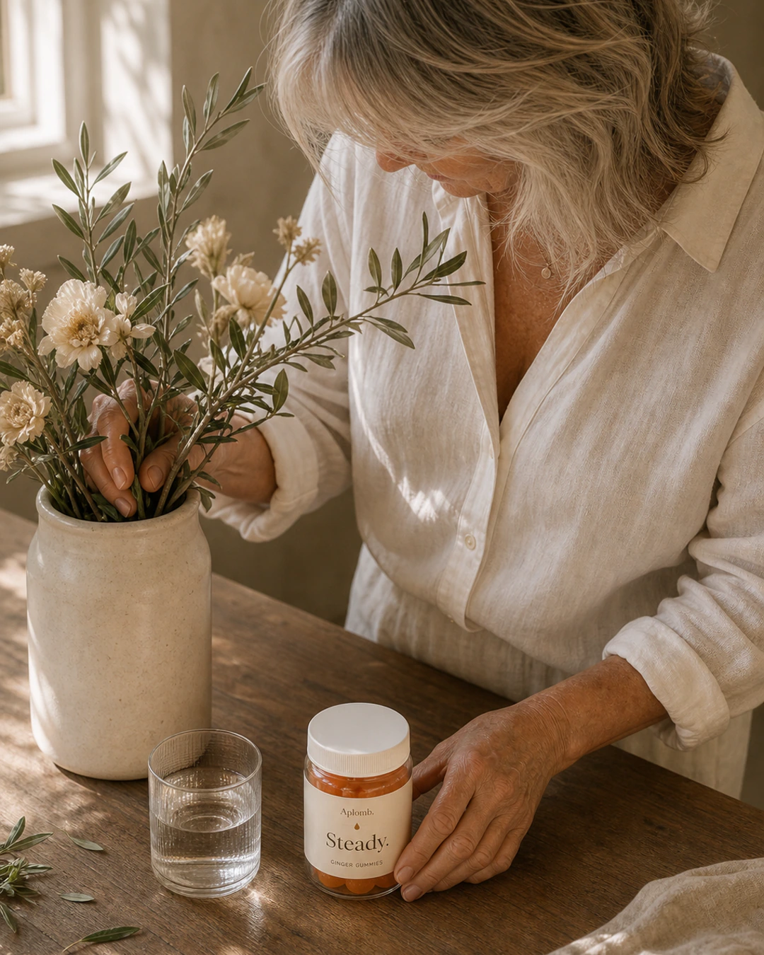 Woman arranging flowers with APLOMB Steady and a glass of water nearby
