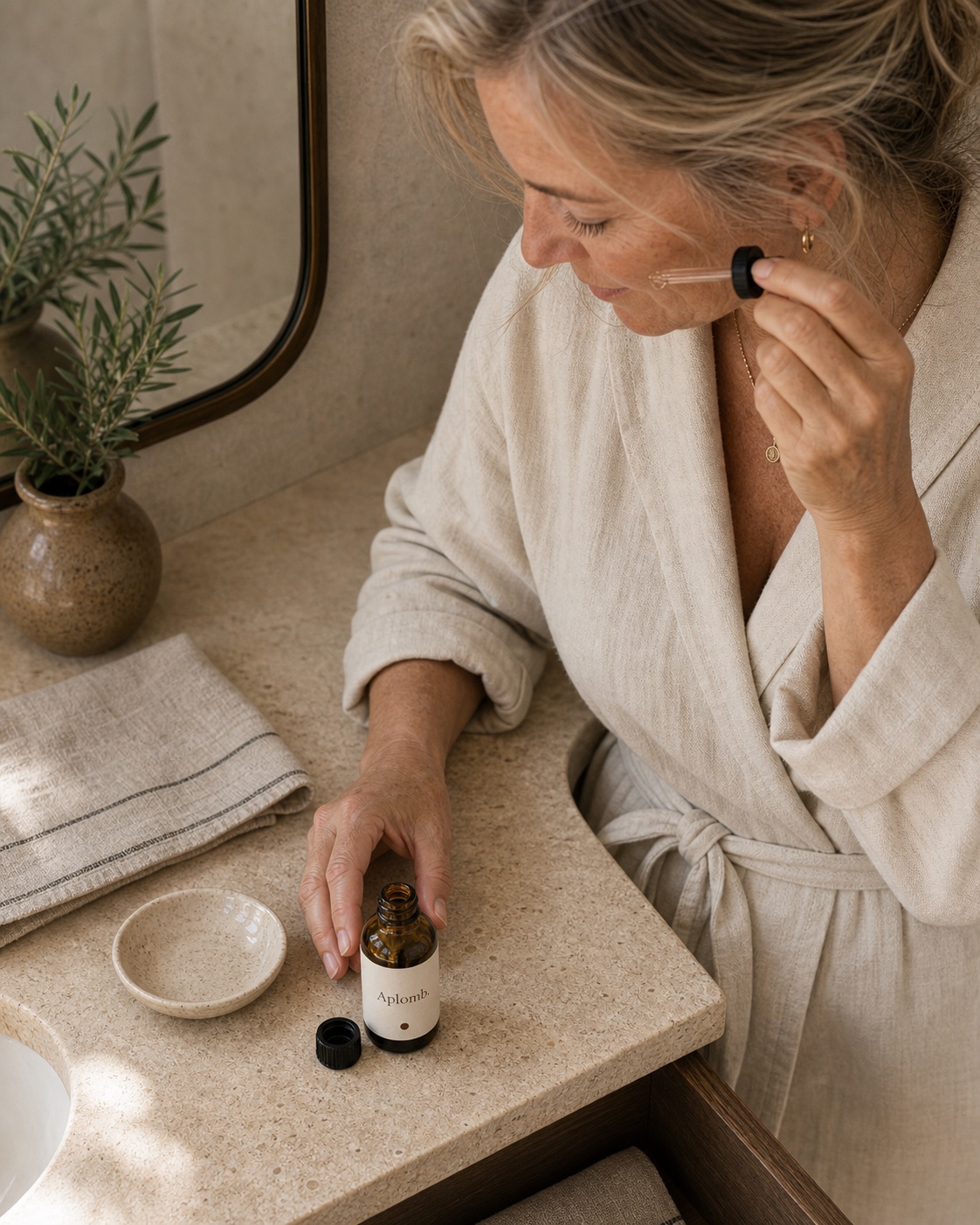 A woman applying APLOMB Facial Serum in morning light
